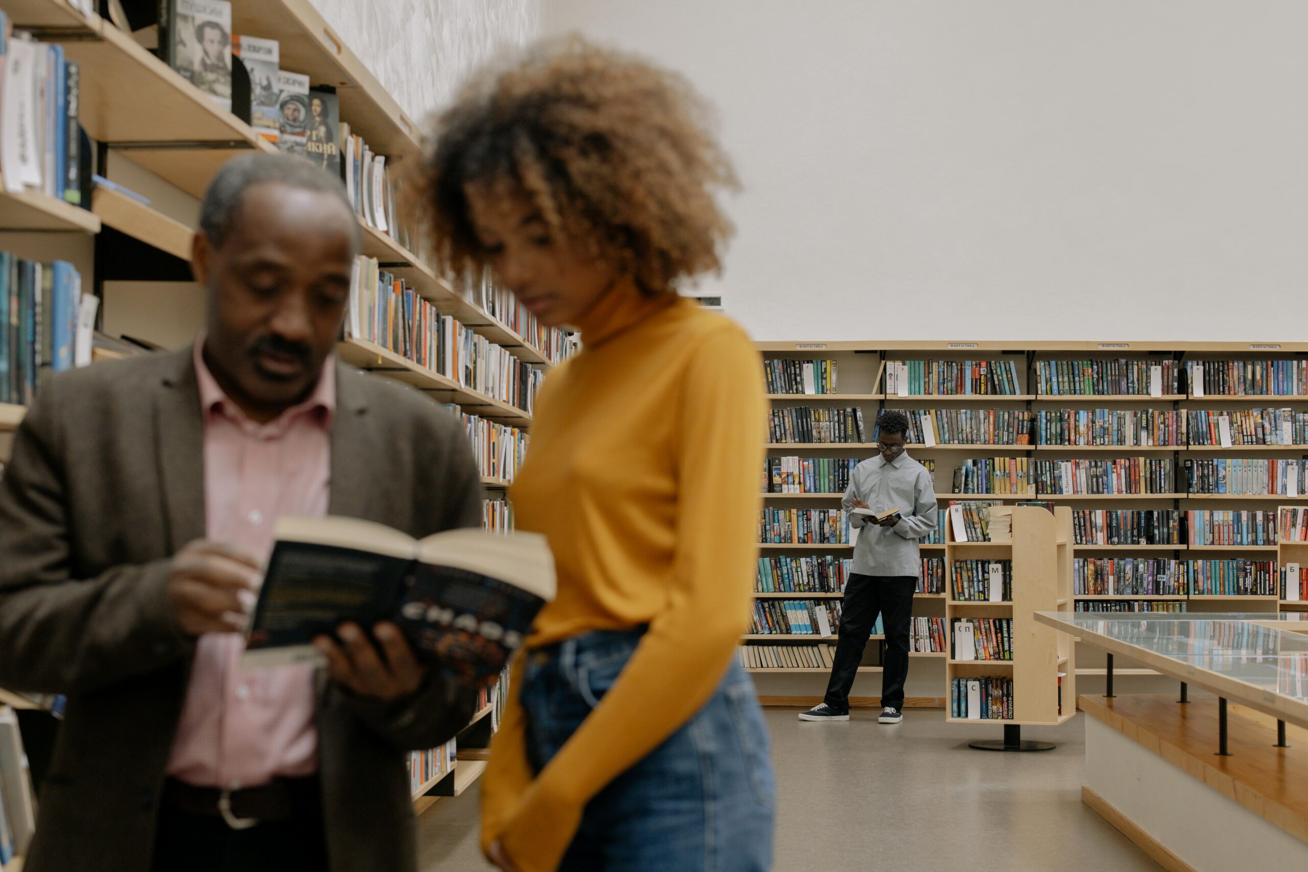 People reading and studying in a modern library setting, promoting education and diversity.